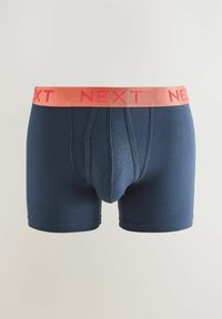Temno modri bokseric s breskevim elastičnim pasom, na katerem je vtisnjena blagovna znamka "NEXT". Mehak material z gladko teksturo.