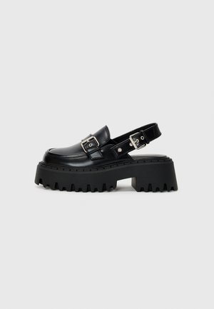 Sort læder chunky plateausko med kraftig sål, sølvspænde detaljer og åben slingback rem.