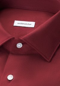 Bordeaux knoop-overhemd met een gladde textuur, voorzien van een scherpe kraag en een wit "seidensticker" label nabij de kraag.