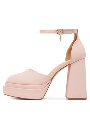 Różowe sandały na platformie z zaokrąglonym noskiem i grubym, blokowym obcasem. Pasek wokół kostki ma złotą klamrę i ozdobny łańcuszek.