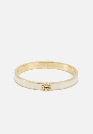 Pulseira bangle em tom dourado, com uma banda de esmalte branco e um acento decorativo dourado no centro, formato redondo, textura suave.