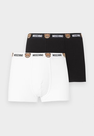 To par herretrusser, én sort og én hvid, hver med et mærket elastik med bamseansigter og teksten "MOSCHINO".