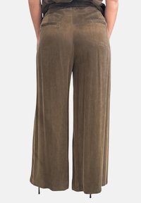 Pantaloni a gamba larga in verde oliva, realizzati con un tessuto morbido e strutturato. Sul retro presentano due tasche e una cintura elastica per il massimo comfort.