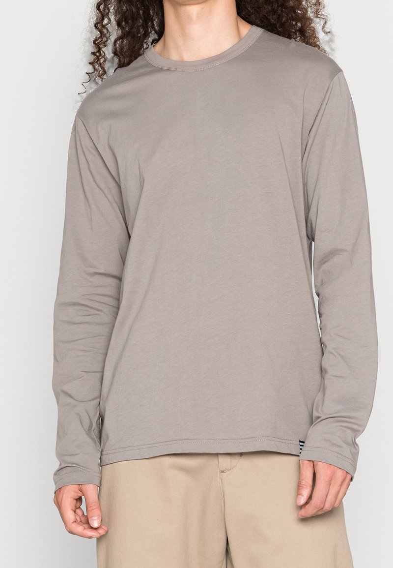 Langarmshirt in Hellgrau. Hergestellt aus weichem Stoff, zeichnet es sich durch einen klassischen Rundhalsausschnitt und minimale Nähdetails aus.