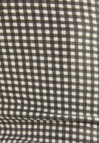 Black and white gingham fabric featuring a small check pattern. Material appears woven with a soft texture and structured shape.