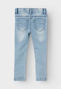 Jeans de mezclilla azul claro con corte ajustado, que cuentan con dos bolsillos traseros y una cintura cosida. Las áreas desgastadas aportan textura a la tela.
