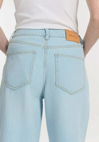 Lichtblauwe denim jeans met een hoge taille, twee achterzakken en een leren label met "labdip" op de tailleband.