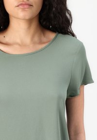 Lys grøn kortærmet t-shirt med rund halsudskæring og glat, struktureret stof. Enkel design med minimale detaljer.