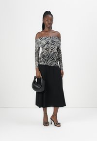 Off-shoulder topp med zebra-mønster, kombinert med et svart midiskjørt. Tilbehør med en svart veske og utsmykkede høye hæler.