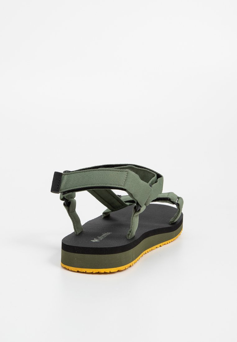 Zewnętrzne sandały z zielonymi regulowanymi paskami z tkaniny, czarną wyściełaną podeszwą i żółtą teksturowaną gumową podeszwą, zwróconą tyłem, na białym tle.