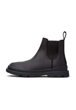 Botín Chelsea de cuero negro con paneles laterales elásticos, acabado texturizado, puntera redondeada y suela gruesa de goma. Presenta una lengüeta trasera.