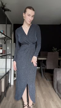 Pitkä, tummanharmaa, venyvistä kankaista valmistettu mekko, jossa on kietaisuosa, V-kaula-aukko, pitkät hihat ja reiden yli ulottuva halkio, yhdistetty mustiin nauhakenkiin.