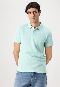 Heleda tealkirju polo särk, mis on valmistatud puuvillast, valge krae ja väikese logoga rinnal. Lühikesed varrukad ja mugav lõige. Denimihallid teksapüksid.