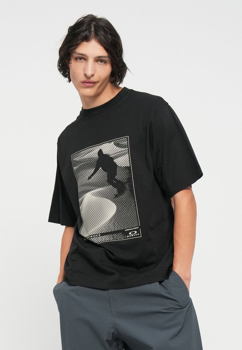 T-shirt nera in cotone con un design grafico di uno snowboarder, incorniciato da linee diagonali e uno sfondo astratto sfumato. Maniche corte.