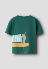 Grøn bomulds t-shirt med korte ærmer, der har et tegneserie design af en hund på en skateboard og et stribet tæppe mønster.