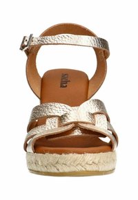 Gold metallic sandal with a woven espadrille sole, featuring a wide strap design and ankle buckle, showcasing a textured finish.