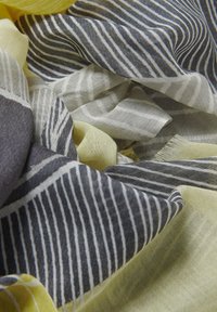 Tejido ligero y multirrayado con colores gris oscuro, gris claro y amarillo. Textura suave con bordes deshilachados y anchos de rayas variados.