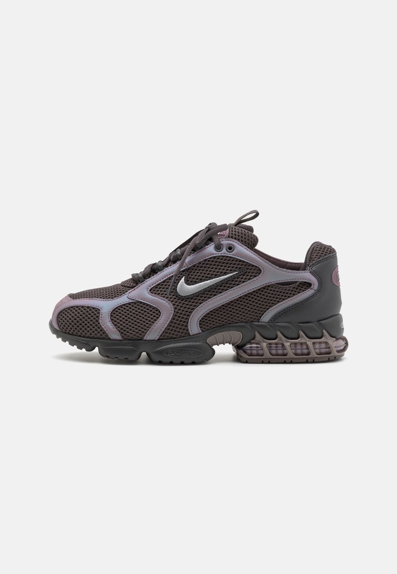 Chaussure de course Nike gris foncé avec dessus en mesh, logo argenté, semelle rembourrée et fermeture à lacets vue de profil sur fond blanc.