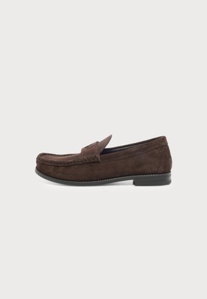 Mocassin homme en daim marron avec semelle noire et détails cousus, présenté en vue latérale sur fond uni.