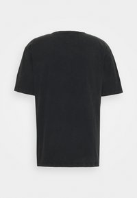 Camiseta negra de algodón con cuello redondo y mangas cortas. El diseño es simple, con un corte relajado y un color sólido sin estampados.