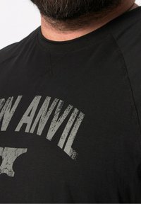 Černé tričko s krátkým rukávem s texturovaným šedým grafickým potiskem obsahujícím slova "IRON ANVIL" a stylizovaný design kovadliny.