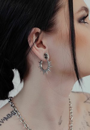 Silberohrringe mit einem kreisförmigen Design, das einen gespickten äußeren Rand und einen abgerundeten Stecker aufweist, mit einem polierten Finish und modernem ästhetischem Aussehen.