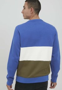 Felpa a blocchi di colore blu, bianca e verde oliva con maniche lunghe, polsini a coste e collo girocollo. Texture morbida, design casual.