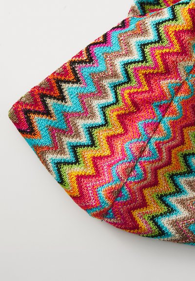 Farbenfroher Stoff mit Zickzack-Muster in Pink, Blau, Braun und Grün. Das Material wirkt strukturiert mit einem gewebten Design. Oberer Rand gefaltet.