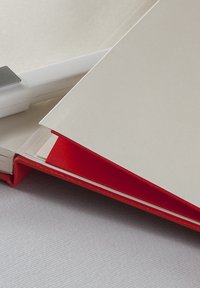 Raccoglitore rosso con una finitura liscia, dotato di un inserto per cartelle di colore chiaro. Sono visibili angoli netti e un materiale lucido.