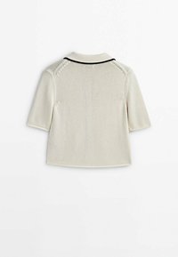 Koszulka z krótkim rękawem w jasnobeżowym kolorze, wykonana z dzianiny, z żebrowanym kołnierzem i czarną lamówką, posiadająca fakturowany wzór i prosty dół.