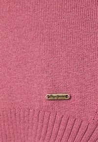 Gestreifter rosa Pullover mit einem gerippten Saum und einem kleinen Metall-Logoschild mit dem Text "Pepe Jeans." Weiche Textur, mittleres Strickmuster.
