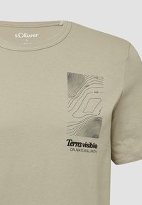 Beżowy t-shirt z wzorem mapy konturowej i napisem "Terra visible ON NATURAL PATH" na lewej piersi, metka rozmiaru s.Oliver L wewnątrz kołnierza.