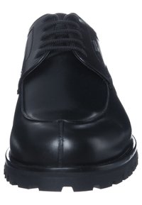 Chaussure en cuir noir avec un bout arrondi, fermeture à lacets et semelle texturée. Finition lisse avec des coutures subtile et des accents de panneaux.