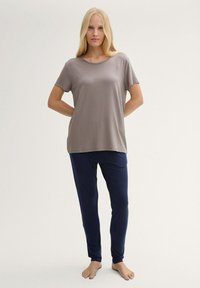 Grå t-shirt med kort ärm och rund halsringning, parat med mörkblå, raka pyjamasbyxor. Mjuk tyg med en slät textur.