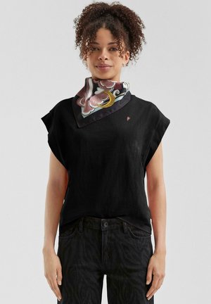 Haut noir à manches courtes avec un col rond et un tissu léger, associé à un foulard en soie à motifs floraux en rose et bleu.