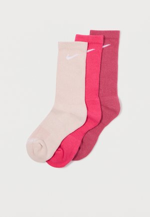 Tres pares de calcetines de canalé en beige claro, rosa brillante y burdeos profundo, con un logo blanco de Nike en el par beige claro.