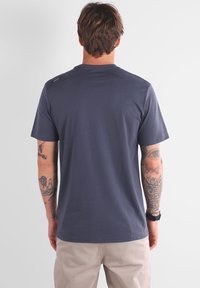 T-shirt bleu marine à manches courtes avec un col rond, texture lisse et un petit logo sur l'épaule. Convient pour un usage décontracté.