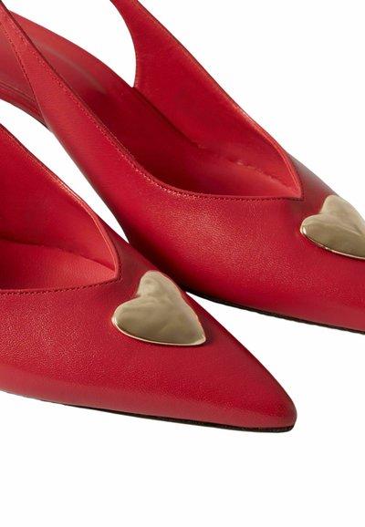 Zapatos de tacón rojo con tira trasera, adornados con corazones dorados en la punta, hechos de cuero suave.
