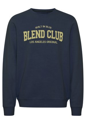 Tamnodijeli plavi dukserica s okruglim izrezom, dugim rukavima i rebrastim manžetama. Sadrži veliki žuti natpis "BLEND CLUB LOS ANGELES ORIGINAL."