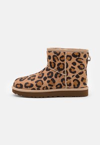 Leopard-print ankle boots made of soft suede with a rounded toe, plush interior, and textured rubber sole. Side pull tab for easy wear.