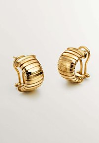 Pendientes de aro de oro con un diseño estriado, una superficie lisa y reflectante, y un cierre de seguridad.
