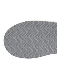 Suela de zapato de goma con un patrón ondulado, predominantemente gris con una textura lisa y un borde redondeado. Sin marcas visibles ni detalles.