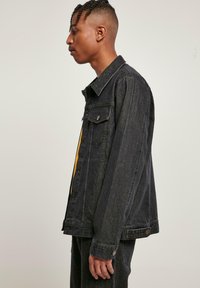 Svart denimjakke med klassisk design, som har to brystlommer, knappefeste og en litt oversized passform. Glatt tekstur.
