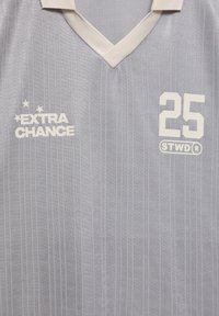 Šedý športový dres s vertikálnymi pruhmi, výstrihom do V, logom "EXTRA CHANCE", číslom "25" a bielym brandingom "STWD®".