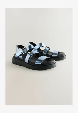Blaue metallische Sandalen mit mehreren Riemen, verstellbaren Schnallen und einer klobigen schwarzen Sohle. Besitzt eine strukturierte Oberfläche und ein offenes Design.
