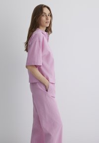 Light pink set featuring striped short-sleeve shirt with a collar and matching wide-leg pants, both with a relaxed fit and soft texture.