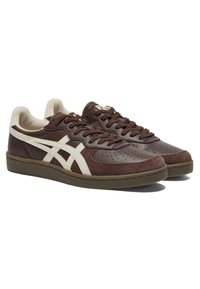 Brown suede and leather sneakers with white accents, perforated design on the toe, and a rubber sole. Features brown laces and low profile.