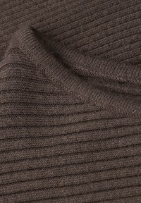 Bruine gebreide stof met een getextureerd, ribbelpatroon. Het materiaal lijkt zacht en iets dik, met consistente lijnen en subtiele elasticiteit.