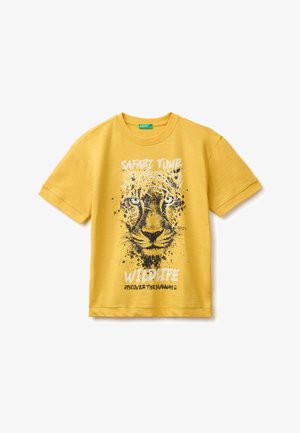 Żółta koszulka z krótkim rękawem z dużą czarno-białą grafiką twarzy lwa i tekstem "Safari Tour Wildlife Discover the Savannah."