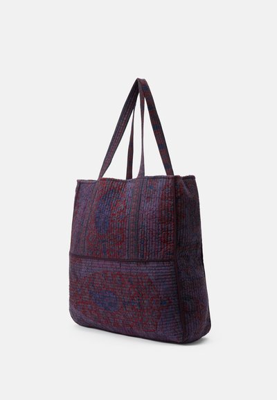 Prešívaná taška v purpurovej a červenej farbe s dvojitými popruhmi, štruktúrovaným tvarom, textúrovaným povrchom a kontrastnou horizontálnou panelou na spodnej časti.